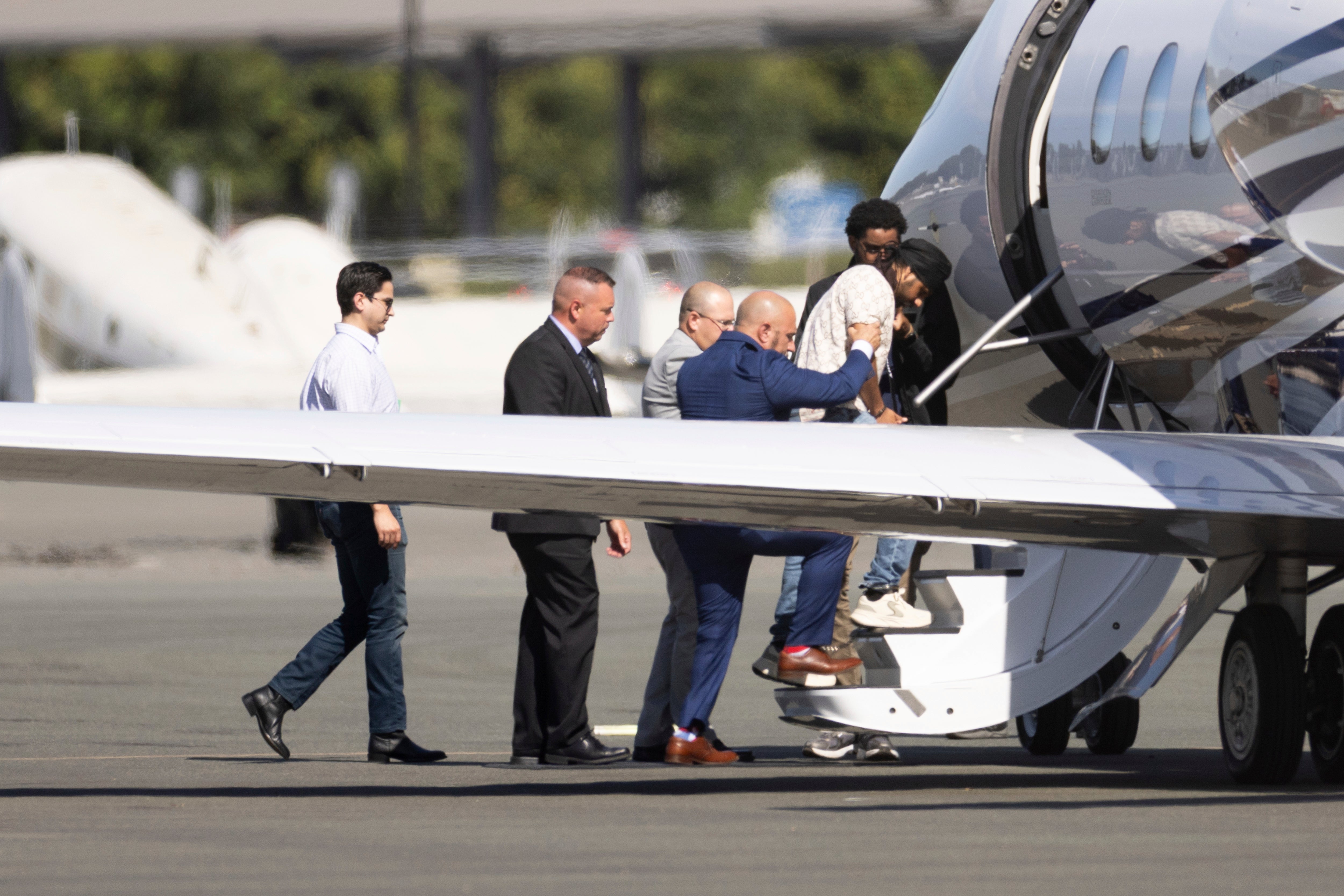 Harjinder Singh is escorted onto an airplane by Florida Lt. Gov. Jay Collins and law enforcement on Thursday in Stockton, California