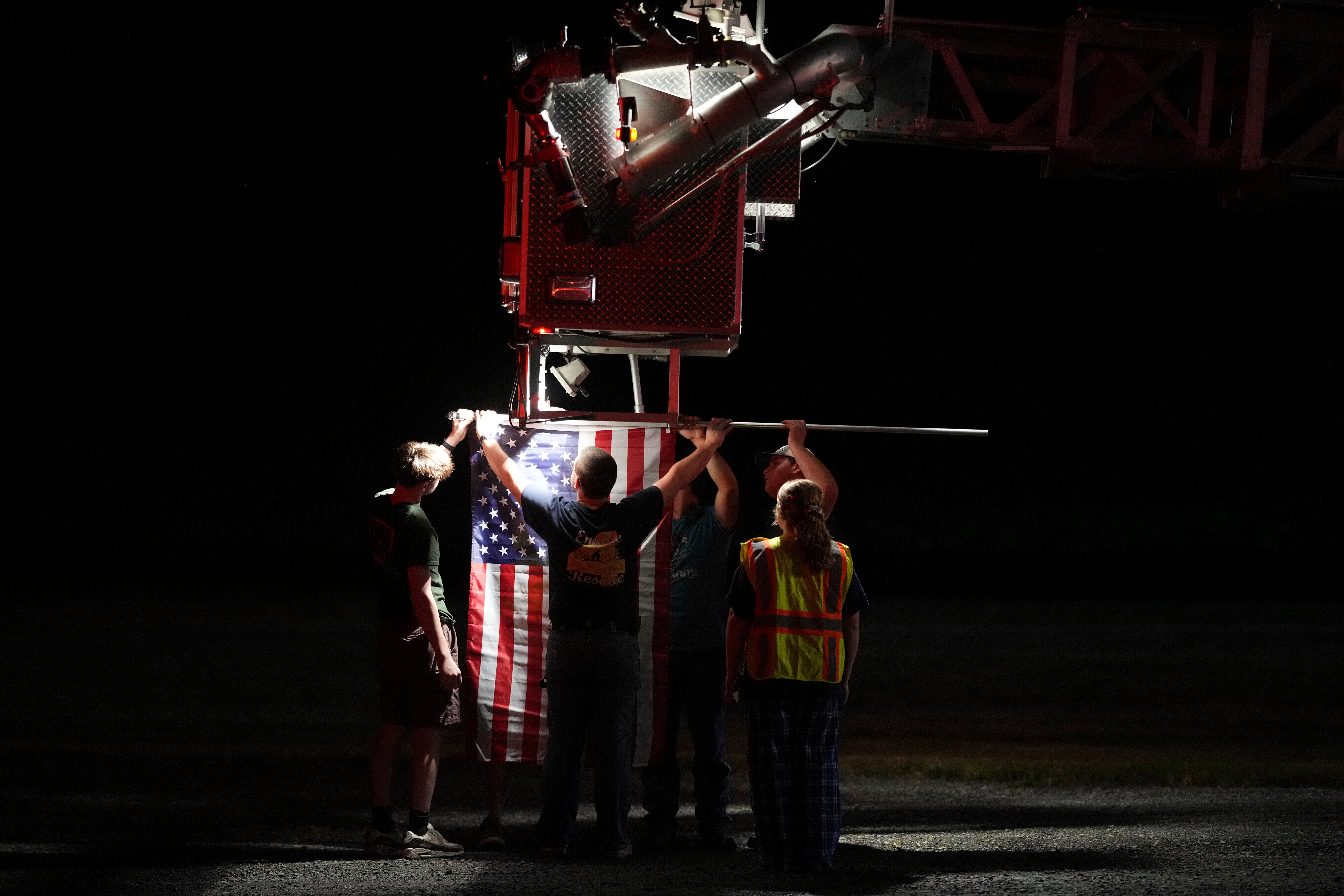 Firefighters attach an American flag to a firetruck before a procession after multiple police officers were shot and killed Wednesday, Sept. 17, 2025, in Spring Grove, Pa. (AP Photo/Matt Slocum)
