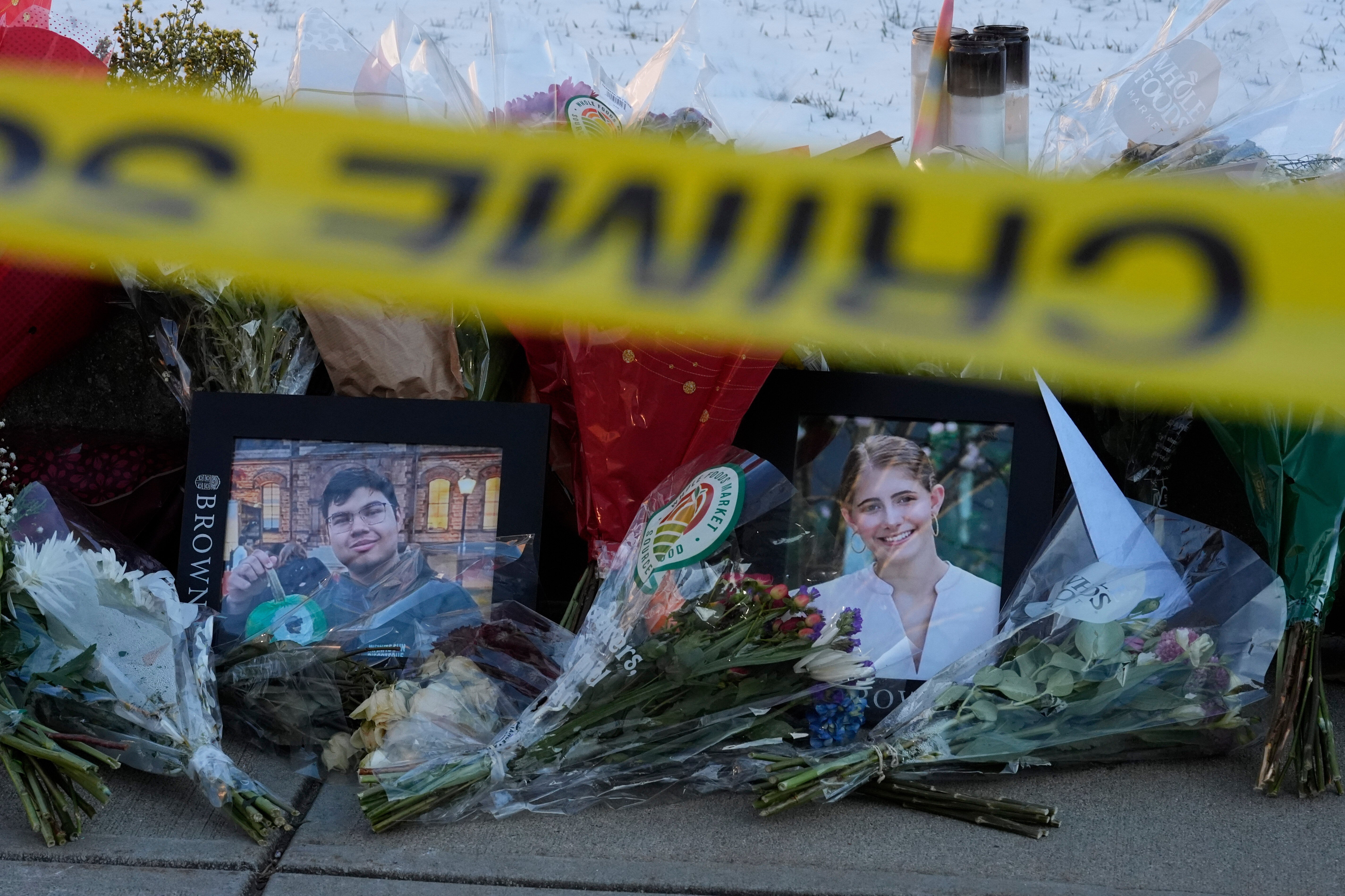Photos of Mukhammad Aziz Umurzokov and Ella Cook sit next to bouquets of flowers at a memorial on Brown University’s campus